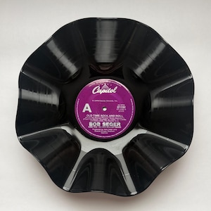 May include: A black vinyl record shaped into a bowl with ruffled edges. The center purple label features the Capitol logo and text: Old Time Rock and Roll, Bob Seger and the Silver Bullet Band, 1978 Capitol Records, Inc., 45 RPM, CP-1192.
