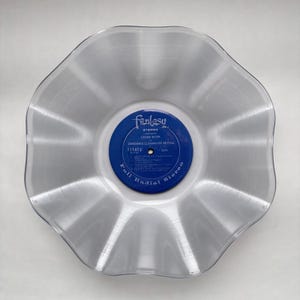 May include: A clear, wavy-edged vinyl record bowl featuring a blue Fantasy label in the center. The label displays the text "Fantasy Presents Green River by Creedence Clearwater Revival" and "Full Radial Stereo" with track listings.