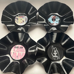 May include: Four black vinyl record bowls with ruffled edges. The centers feature labels for Alice in Chains Down in a Hole, The Soul Survivors, Pearl Jam Ten, and a Rage Against the Machine graphic with a white silhouette of a person raising a fist.