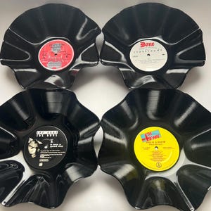 May include: Four black vinyl record bowls with scalloped edges. The top left features a red Death Row Records label, the top right a white Bone Thugs-N-Harmony label, the bottom left an Ice Cube label, and the bottom right a yellow Eric B. & Hakim label.