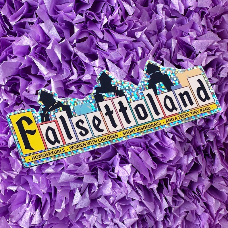 May include: A sticker featuring a glittery, rainbow-coloured cityscape design. The text "Falsettoland" is written in black letters across the cityscape. Below the cityscape, the text reads "Homosexuals, Women with Children, Short Insomniacs, and a Teeny Tiny Band."