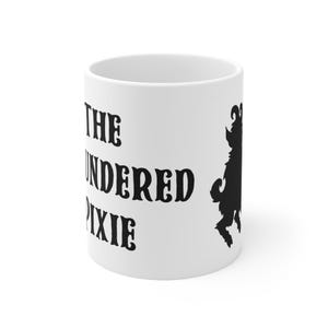 Könnte beinhalten: Weißer Keramikbecher mit dem schwarzen Text "THE UNDERED PIXIE" und einer schwarzen Silhouette einer Kreatur. Der Becher hat eine zylindrische Form und ist von normaler Kaffeetassengröße.