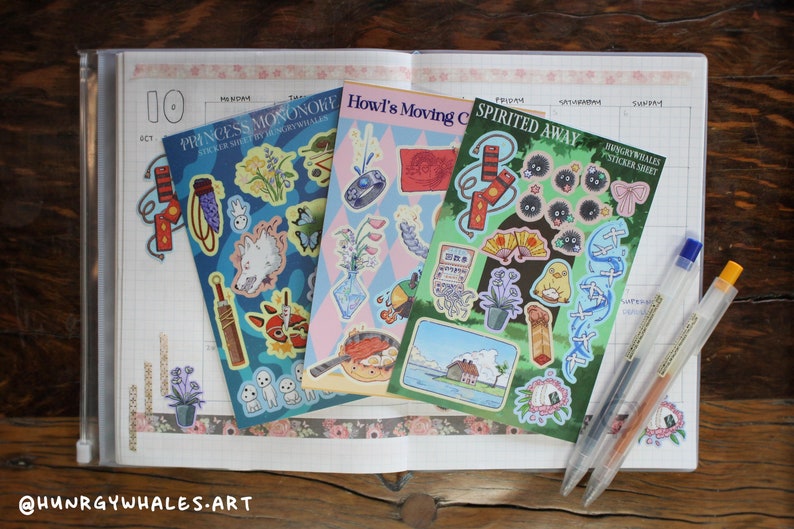 Spirited Away, Howl's Moving Castle, and Princess Mononoke sticker sheets on top of a planner.