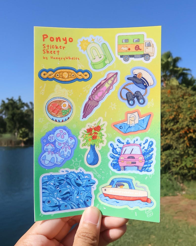 May include: A sticker sheet featuring cartoon illustrations of a pink car, a boat, a truck, and a squid. The sheet is labelled "Ponyo Sticker Sheet by HungryWhales". The background is a gradient of green and yellow, with a hand holding the sheet.