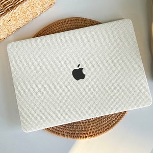 May include: White laptop case with a woven texture and a black Apple logo.