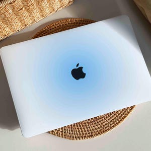 May include: A white laptop computer with a blue gradient on the lid. The Apple logo is visible on the lid.