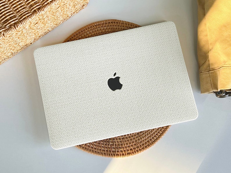 May include: White laptop case with a woven texture and a black Apple logo.