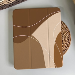 May include: A brown and beige iPad case with a geometric abstract design. The case has a textured surface and is made of a durable material.