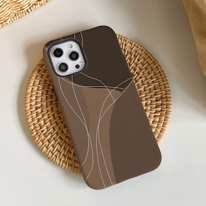 Può includere: Una custodia per telefono marrone con un design astratto bianco. La custodia ha un ritaglio per l'obiettivo della fotocamera e un bordo rialzato attorno ai bordi.