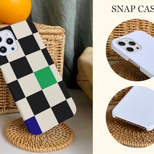 K&ouml;nnte beinhalten: Eine Handyh&uuml;lle mit einem schwarz-wei&szlig;en Karomuster und einem gr&uuml;nen Quadrat. Die H&uuml;lle liegt auf einer Oberfl&auml;che aus Weidengeflecht. Der Text "SNAP CASE" befindet sich in der oberen rechten Ecke des Bildes.