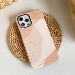 Puede incluir: Una funda para teléfono con un diseño abstracto beige y marrón. La funda tiene un recorte para la lente de la cámara.