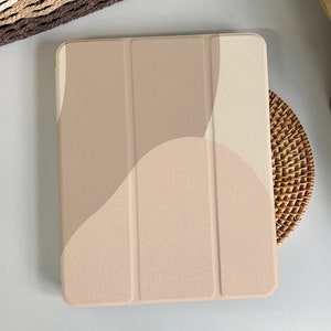 Op de afbeelding: Een beige iPad-hoes met een geometrisch patroon van overlappende cirkels. De hoes is gemaakt van een zacht, gestructureerd materiaal.