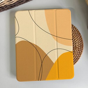 May include: A beige, brown, and yellow tablet case with an abstract design featuring curved lines and shapes.