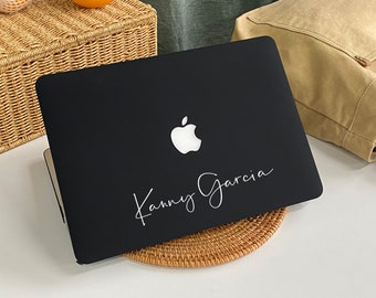 May include: Black laptop case with a white Apple logo and the name "Kenny Garcia" written in cursive.