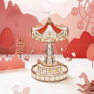 May include: A wooden carousel model with a red and white striped canopy and hanging seats. The carousel has intricate details and is illuminated with lights. The background features a pink landscape with a Ferris wheel and other amusement park elements.