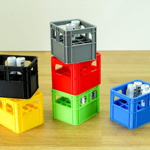 Puede incluir: Cinco cajas de plástico de diferentes colores con compartimentos para baterías. Las cajas están apiladas unas sobre otras. Las cajas son grises, rojas, verdes, amarillas y azules.