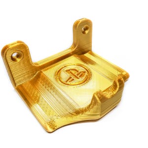 May include: A gold-colored 3D printed wall mount for a video game controller. The mount features a PlayStation logo.