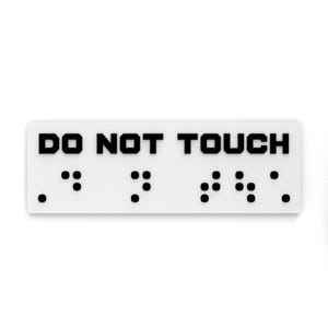 May include: A white rectangular sign with black text that reads "DO NOT TOUCH" in all caps. The sign also includes braille lettering.