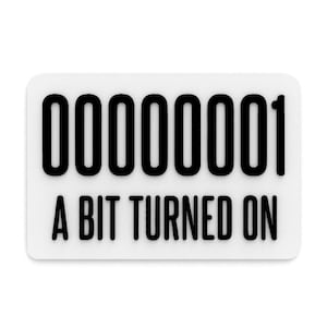 Pode incluir: Um autocolante retangular branco com cantos arredondados. O texto preto em negrito diz "00000001" acima de "A BIT TURNED ON". O autocolante tem um design limpo e minimalista.