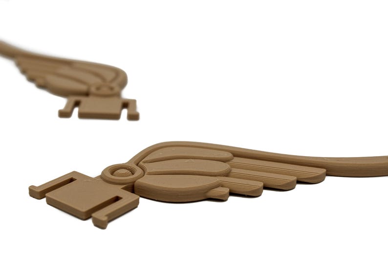 May include: Two brown plastic wings with a detailed design. The wings are curved and have a textured surface.