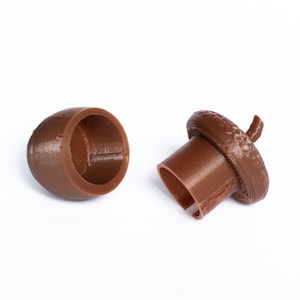 May include: Two brown acorn-shaped bottle stoppers, one with the top removed to show the hollow interior.