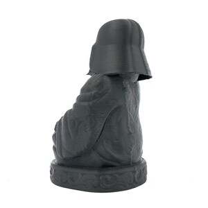 Puede incluir: Una figura negra de Darth Vader impresa en 3D sentado en una postura meditativa. La figura est&aacute; detallada con intrincados patrones y una superficie texturizada.