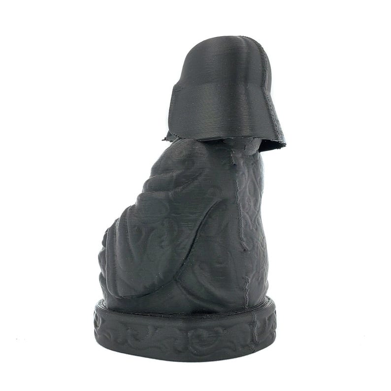 Puede incluir: Una figura negra de Darth Vader impresa en 3D sentado en una postura meditativa. La figura est&aacute; detallada con intrincados patrones y una superficie texturizada.