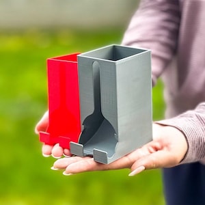 May include: Two 3D printed storage boxes, one red and one gray, with a slot for holding items. The boxes are held in a person's hand.