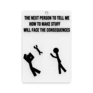 May include: White rectangular sign with black text: "THE NEXT PERSON TO TELL ME HOW TO MAKE STUFF WILL FACE THE CONSEQUENCES." Features stick figures and a wrench graphic. A hole is at the top for hanging.