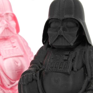 Puede incluir: Dos peque&ntilde;as figuras de un personaje ficticio popular, una en rosa y otra en negro. Las figuras est&aacute;n en posici&oacute;n sentada con las manos juntas delante de ellas.