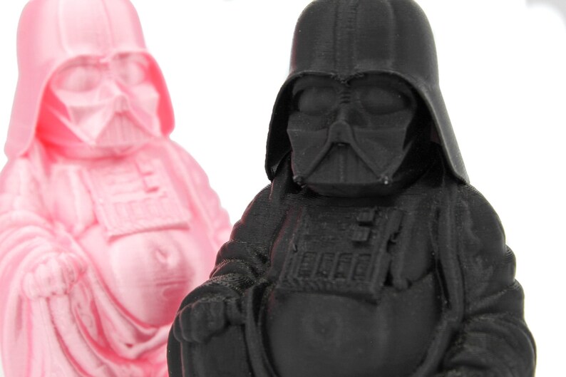 Puede incluir: Dos peque&ntilde;as figuras de un personaje ficticio popular, una en rosa y otra en negro. Las figuras est&aacute;n en posici&oacute;n sentada con las manos juntas delante de ellas.