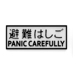 以下が含まれることがあります： 黒い縁と白い背景の長方形のサイン。サインには、英語のフレーズ「PANIC CAREFULLY」の上に日本語の文字が黒のサンセリフ体で表示されています。全体的なデザインはミニマリストでモダンです。