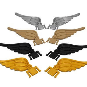 May include: Six pairs of plastic wings in different colors: silver, gold, and black. The wings are designed to be attached to a surface.
