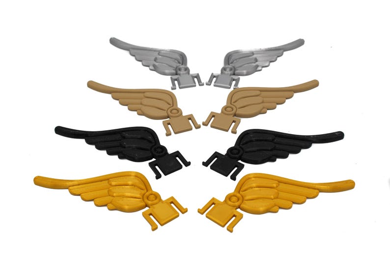 May include: Six pairs of plastic wings in different colors: silver, gold, and black. The wings are designed to be attached to a surface.