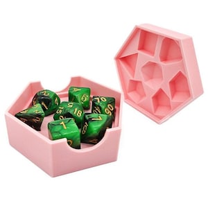 May include: A pink hexagonal dice tray with a lid, containing seven green and black marbled dice with gold numbers. The dice are in a variety of shapes and sizes.