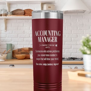 May include: A maroon stainless steel tumbler with a white inscription that reads "ACCOUNTING MANAGER [a- kaün-tin ][ ma-ni-jer noun (n) Someone who solves problems you never knew existed in ways that will blow your mind; See also: ninja; badass; legend"