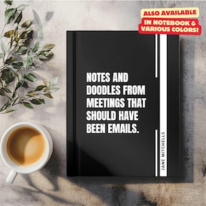 Könnte beinhalten: Schwarzes Notizbuch mit dem Text "NOTES AND DOODLES FROM MEETINGS THAT SHOULD HAVE BEEN EMAILS." und "JANE MITCHELLS" auf dem Cover. Das Notizbuch liegt auf einer hellbraunen Oberfläche mit einer grünen Pflanze und einer Tasse Kaffee.
