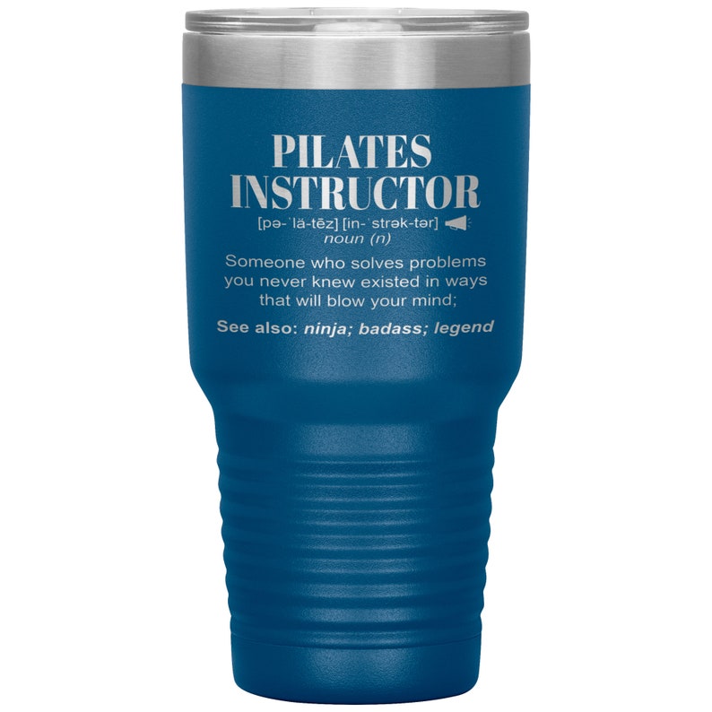 May include: A blue stainless steel tumbler with a white inscription that reads "PILATES INSTRUCTOR [pə-l&auml;-tēz] [in- strək-tər] noun (n) Someone who solves problems you never knew existed in ways that will blow your mind; See also: ninja; badass; legend"