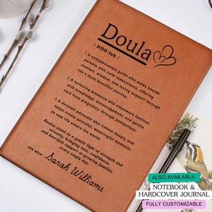 May include: A brown leather-bound journal with the word "Doula" printed on the cover, along with a definition and the name "Sarah Williams." The journal also includes a heart graphic and text describing the role of a doula. Also available: Notebook & Hardcover Journal.