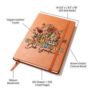 Op de afbeelding: Een bruin veganistisch lederen notitieboek met een bloemenontwerp en de tekst "Chaos Coordinator Deb Goodwin". Het notitieboek heeft een lint-bladwijzer, een bruin elastisch sluitband en meet 14,7 cm breed en 21,6 cm lang. Het bevat 100 vellen gelinieerd papier.