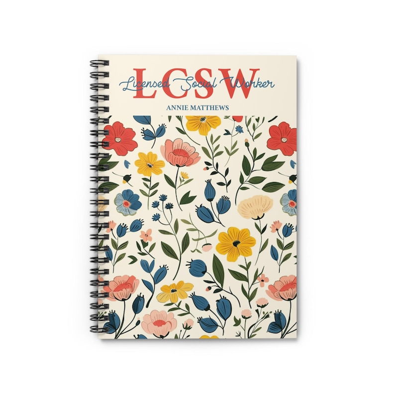 K&ouml;nnte beinhalten: Spiralgebundenes Notizbuch mit floralem Muster. Das Cover zeigt einen cremefarbenen Hintergrund mit bunten Blumen und gr&uuml;nen Bl&auml;ttern. Der obere Teil des Notizbuchs zeigt den Text "LCSW" in Rot und "Licensed Social Worker" in Blau, darunter der Name "Annie Matthews".