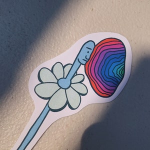 May include: A sticker with a blue and white daisy and a rainbow swirl with a face inside. The swirl is red, orange, yellow, green, blue, indigo, and violet.