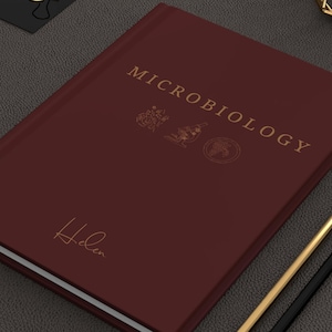Peut inclure: Un journal relié en cuir bordeaux avec le titre "MICROBIOLOGY" en lettres dorées. Le journal est personnalisé avec le nom "Helen" en lettres dorées.