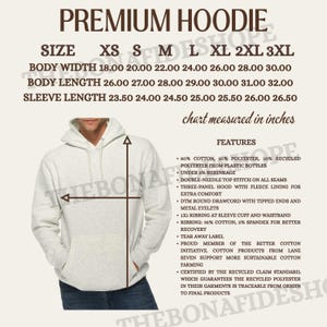May include: A light gray premium hoodie with a size chart showing measurements in inches. The hoodie features a three-panel hood, fleece lining, and ribbed cuffs. The chart lists body width from 18.00 to 30.00 inches.