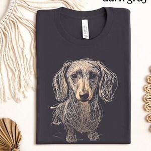 May include: Dark gray t-shirt featuring a sketched dachshund dog design. The dog is depicted in a detailed, line-art style with tan and cream tones. The text "dark gray" is at the top. The shirt has a crew neck and a tag that says "CANVAS".
