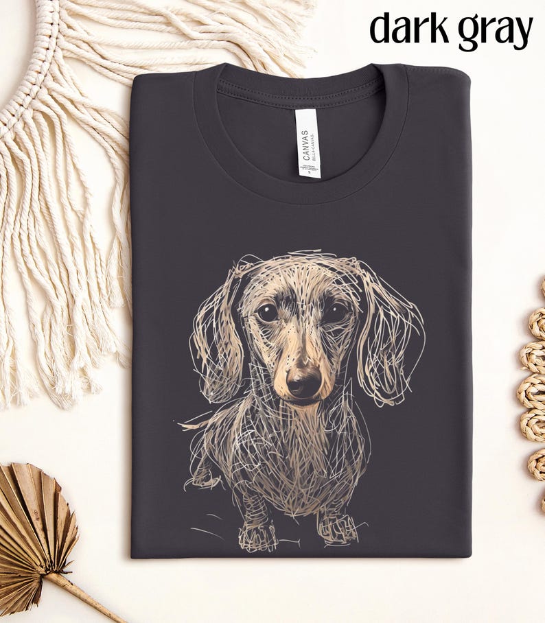May include: Dark gray t-shirt featuring a sketched dachshund dog design. The dog is depicted in a detailed, line-art style with tan and cream tones. The text "dark gray" is at the top. The shirt has a crew neck and a tag that says "CANVAS".