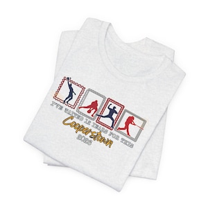 May include: Light gray t-shirt with a sports-themed design. The shirt features four postage stamp-style graphics with silhouettes of athletes in action. Text on the shirt reads "I've waited 12 years for this Cooperstown 2026."