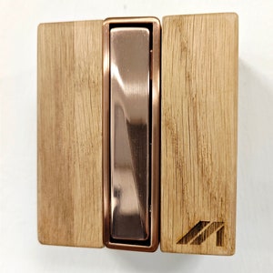 Op de afbeelding: Een houten deurstop voor aan de muur met een koperkleurige metalen insert. Het hout heeft een natuurlijke houtnerf en de metalen insert heeft een geborstelde afwerking.