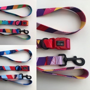 May include: A set of colourful dog collars and leads with geometric patterns. The collars have a red buckle with the word "Leas" printed on it. The leads are adjustable and have a metal clip.
