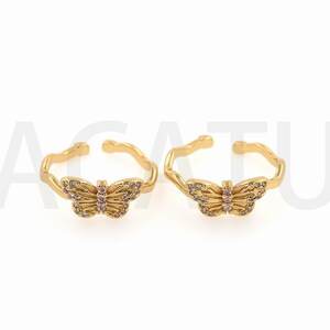 May include: Two gold butterfly rings with clear and pink rhinestones. The rings are open and adjustable.